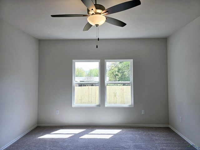 carpeted spare room featuring baseboards and a ceiling fan