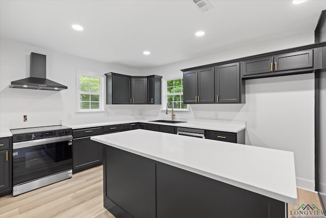 kitchen featuring wall chimney range hood, electric stove, a sink, a healthy amount of sunlight, and visible vents