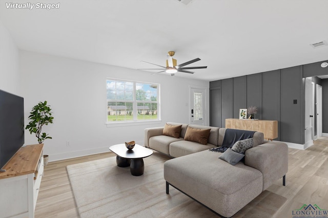 living area with light wood-style flooring, visible vents, a ceiling fan, and baseboards