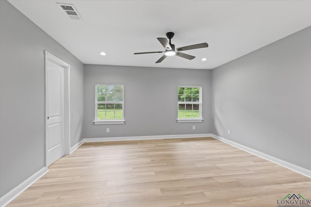 empty room featuring light wood-style floors, visible vents, a wealth of natural light, and ceiling fan