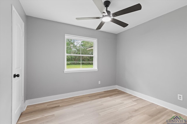 empty room with light wood finished floors, a ceiling fan, and baseboards