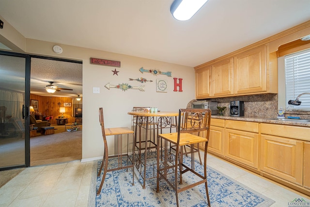 dining space with ceiling fan, wood walls, and sink