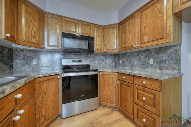 kitchen with tasteful backsplash, stainless steel electric stove, and light hardwood / wood-style floors