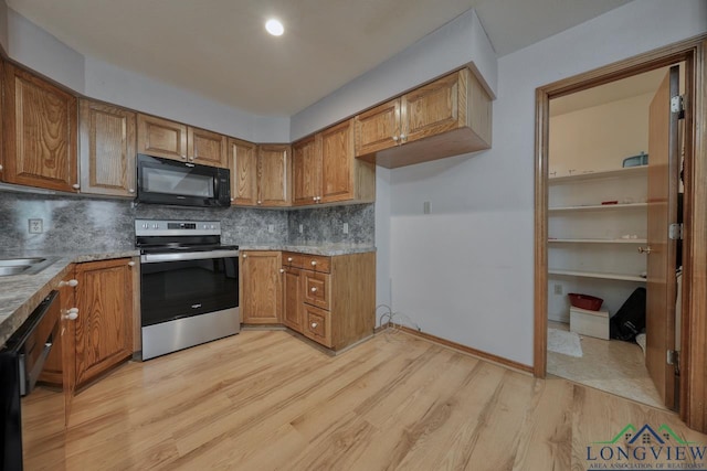 kitchen with tasteful backsplash, sink, light hardwood / wood-style floors, and black appliances