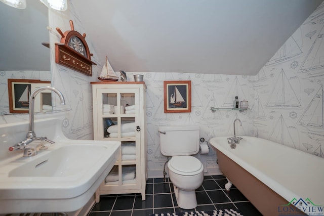 bathroom featuring tile patterned floors, a tub to relax in, toilet, and sink