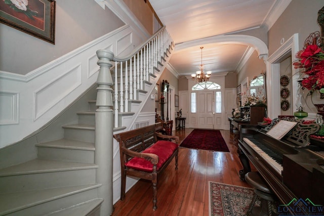 entryway with hardwood / wood-style flooring, ornamental molding, and a chandelier