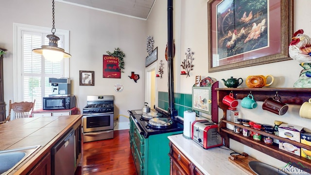 kitchen featuring ornamental molding, stainless steel appliances, dark wood-type flooring, tile countertops, and hanging light fixtures