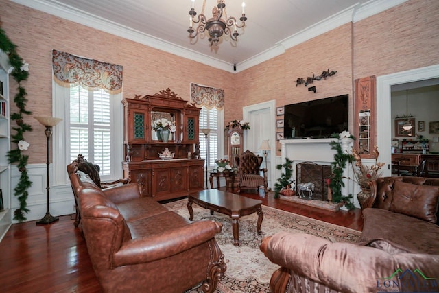 living room featuring a large fireplace, ornamental molding, dark wood-type flooring, and a chandelier