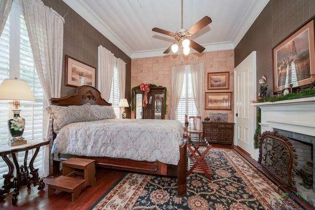 bedroom with a tile fireplace, hardwood / wood-style floors, ceiling fan, and crown molding