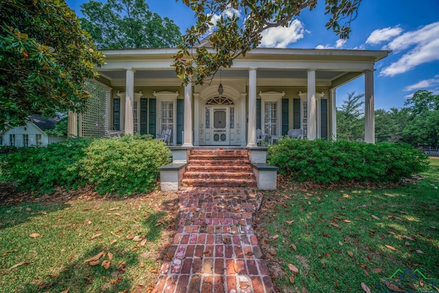 view of exterior entry featuring a yard and covered porch