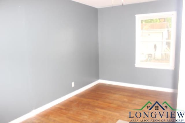 1212 N Edwards St, Gladewater, TX 75647 - spare room featuring baseboards and wood finished floors