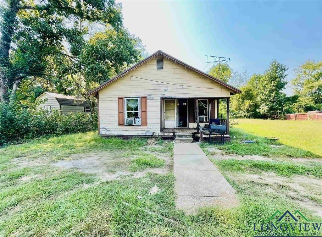 bungalow featuring a front yard, a storage unit, and covered porch