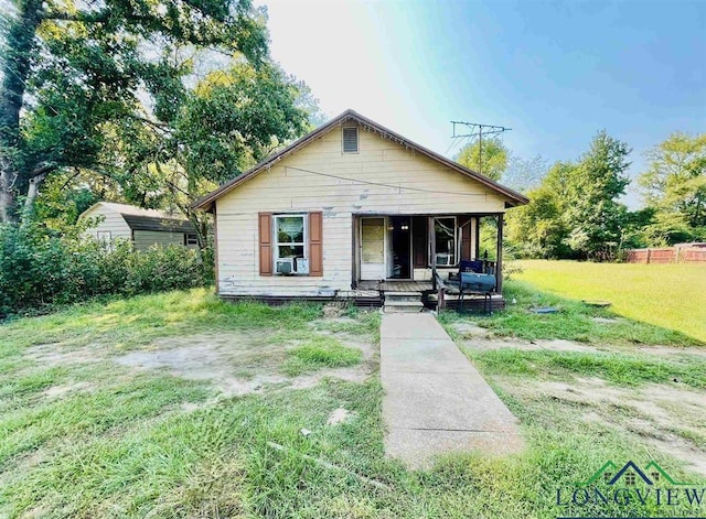 bungalow featuring a front yard, a storage unit, and covered porch