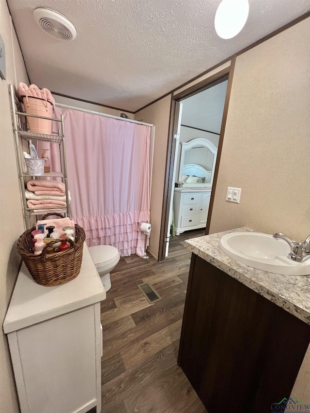 95 Montgomery St, Avinger, TX 75630 - bathroom with wood finished floors, vanity, toilet, a shower with shower curtain, and a textured ceiling