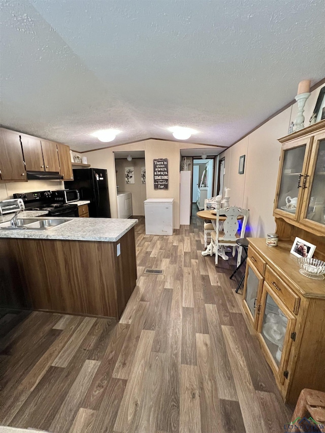 95 Montgomery St, Avinger, TX 75630 - kitchen with black appliances, dark wood-style flooring, a textured ceiling, washer / dryer, and under cabinet range hood