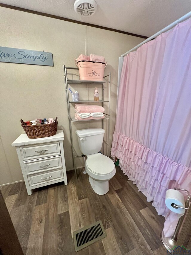 95 Montgomery St, Avinger, TX 75630 - bathroom with wood finished floors, toilet, a shower with curtain, and ornamental molding