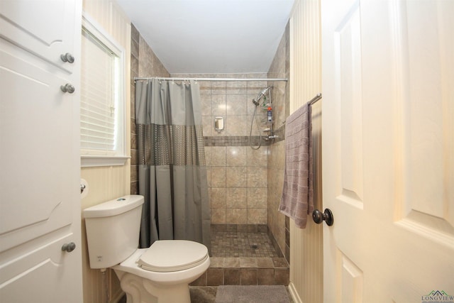 bathroom featuring tiled shower and toilet