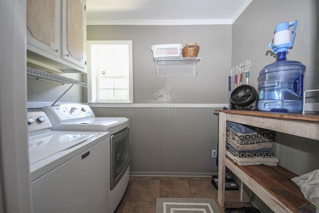 laundry room featuring cabinet space, washing machine and dryer, crown molding, dark tile patterned flooring, and a wainscoted wall