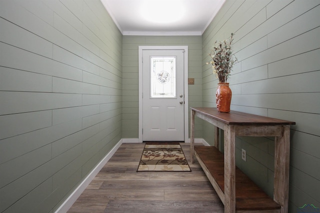 entryway featuring dark wood finished floors, crown molding, baseboards, and wood walls