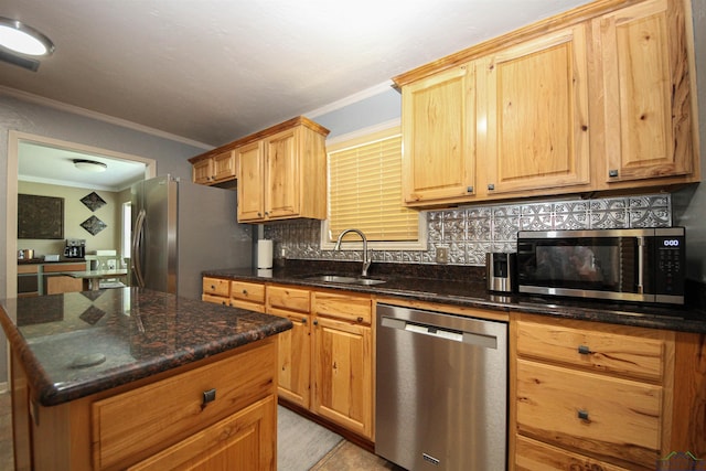 kitchen featuring appliances with stainless steel finishes, a sink, ornamental molding, decorative backsplash, and dark stone countertops