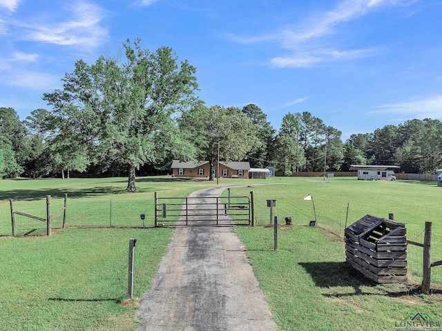 view of home's community featuring a gate, view of wooded area, and asphalt driveway