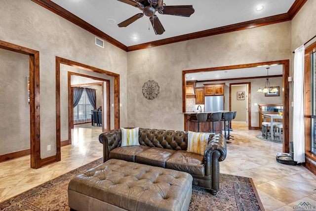 living room featuring crown molding, ceiling fan with notable chandelier, and plenty of natural light