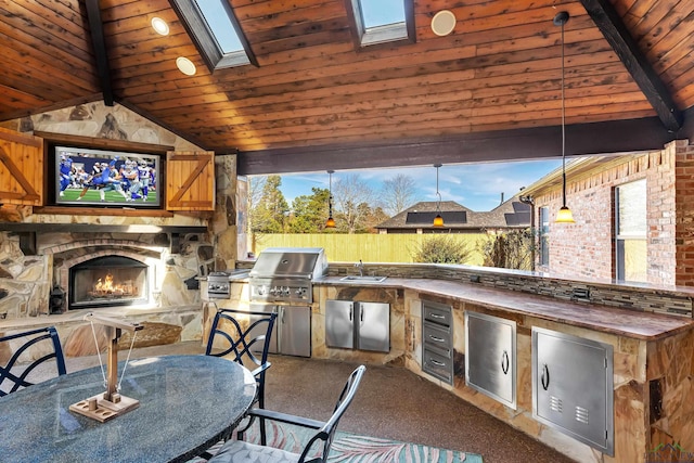 view of patio featuring area for grilling, an outdoor kitchen, a wet bar, and an outdoor stone fireplace