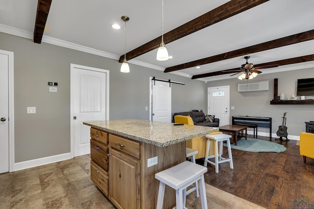 kitchen with a barn door, a center island, a kitchen bar, a wall mounted air conditioner, and hanging light fixtures