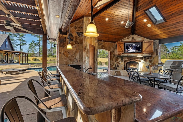 view of patio / terrace featuring an outdoor wet bar, a grill, and an outdoor stone fireplace