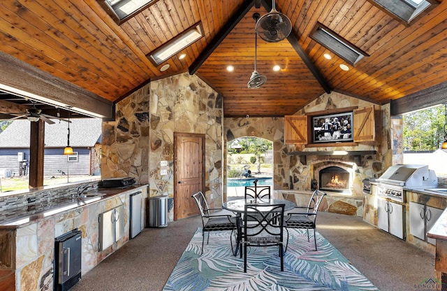 view of patio / terrace with exterior kitchen, a grill, an outdoor stone fireplace, and ceiling fan