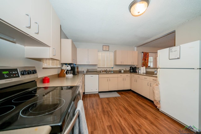 kitchen featuring white appliances, light wood-style flooring, a sink, light countertops, and a textured ceiling