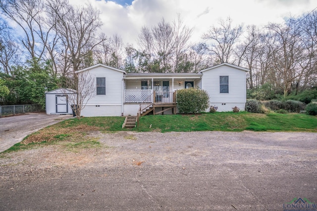 manufactured / mobile home featuring crawl space, covered porch, an outbuilding, and a front lawn