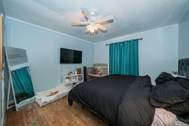 bedroom with a textured ceiling, hardwood / wood-style floors, a ceiling fan, and crown molding