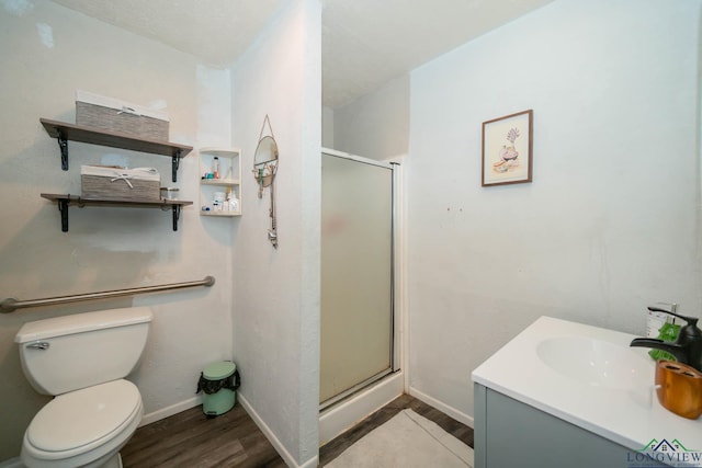 bathroom featuring a shower stall, baseboards, toilet, wood finished floors, and vanity