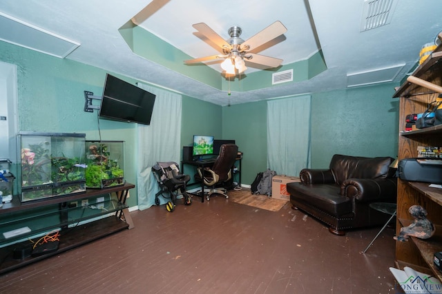 office area with wood finished floors, visible vents, attic access, ceiling fan, and a raised ceiling