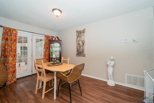 dining area featuring visible vents, baseboards, a textured ceiling, and wood finished floors