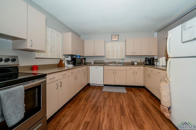 kitchen featuring white cabinetry, white appliances, wood finished floors, and a sink