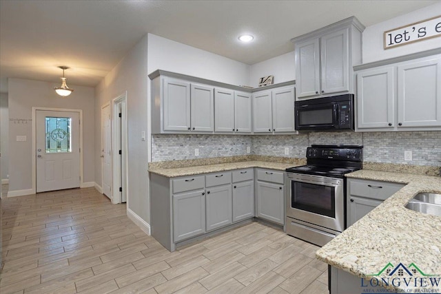 kitchen featuring gray cabinets, decorative backsplash, black microwave, and stainless steel electric stove