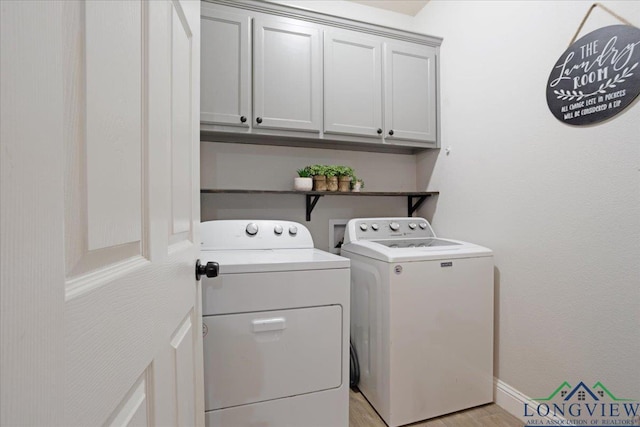 laundry area featuring washing machine and dryer, light wood-style flooring, baseboards, and cabinet space