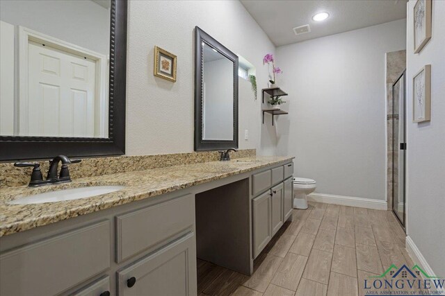 bathroom featuring double vanity, wood finished floors, toilet, and a sink
