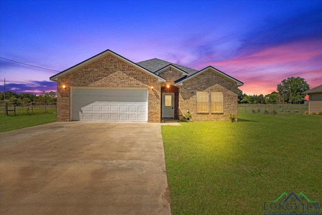 single story home with brick siding, a yard, an attached garage, and driveway