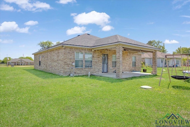 back of property with brick siding, a trampoline, a lawn, and a patio