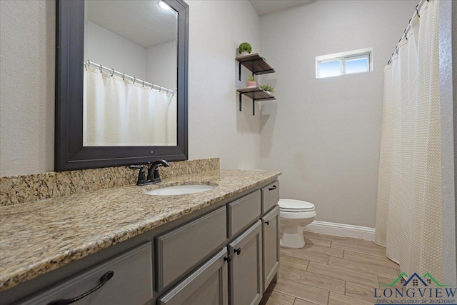 full bathroom featuring wood finished floors, vanity, toilet, and baseboards