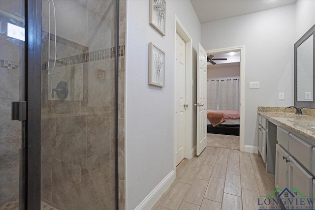 full bathroom featuring vanity, a stall shower, baseboards, ceiling fan, and ensuite bath