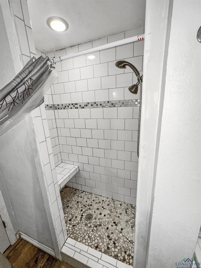 bathroom featuring wood-type flooring and a tile shower