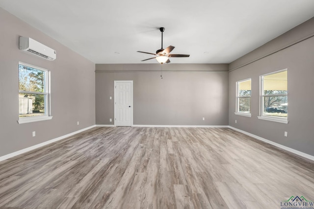 unfurnished room with ceiling fan, light hardwood / wood-style floors, and a wall mounted air conditioner