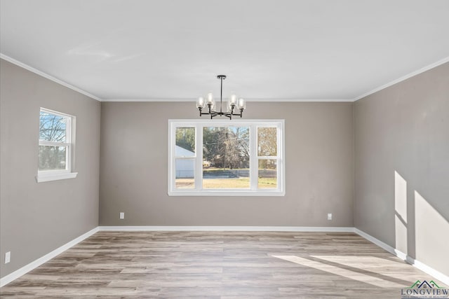 empty room featuring an inviting chandelier, crown molding, and light hardwood / wood-style floors