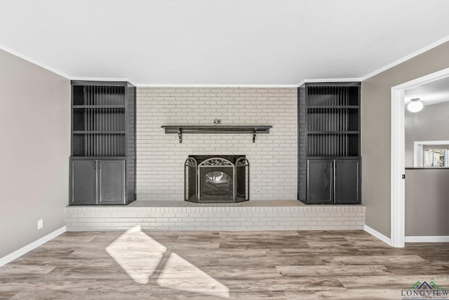 unfurnished living room with built in features, crown molding, a fireplace, and hardwood / wood-style floors