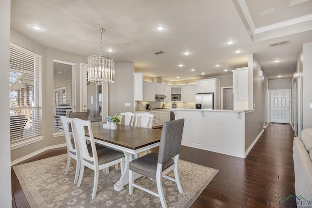 dining space with hardwood / wood-style flooring, ornamental molding, and an inviting chandelier