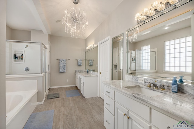 bathroom with hardwood / wood-style flooring, vanity, separate shower and tub, and an inviting chandelier